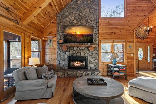 a living room with a stone fireplace in a log cabin at Johnny's Lakeside Hideaway in Morganton