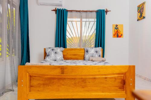 a bedroom with a wooden bed with blue curtains at T3 Duplex - Tsimkoura in Chirongui