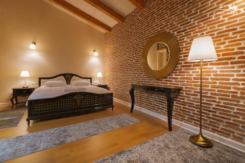 a bedroom with a bed and a brick wall at Casa Gaçe Hotel in Korçë
