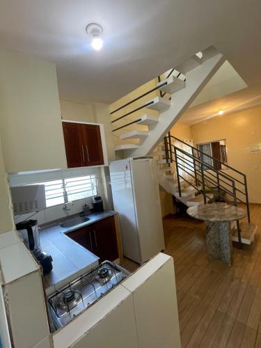 a kitchen with a staircase and a sink and a refrigerator at Casa Aconchego do Mar in Japaratinga