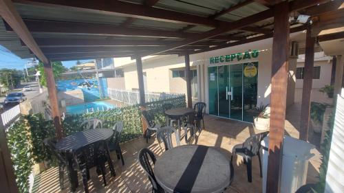 an outdoor patio with tables and chairs and a pool at Pousada Ilha do Itacolomi in Penha