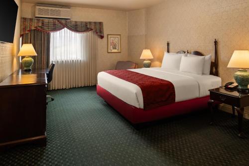 ein Hotelzimmer mit einem großen Bett und einem Schreibtisch in der Unterkunft Carlyle Hotel in Campbell