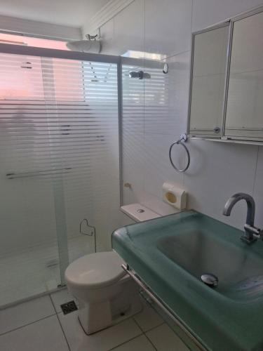 a bathroom with a toilet and a green sink at Apto novo com ampla sacada e piscinas in Guarujá