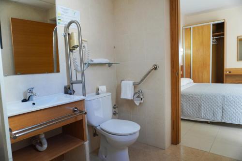 a bathroom with a toilet and a sink and a bed at Hostal Costabella in Fuengirola