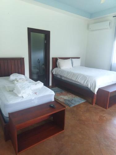 a bedroom with two beds and a table and a mirror at Fishon Panama Lodge in Boca Chica