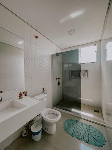 a bathroom with a toilet and a sink and a shower at Suítes em casa ampla com área gourmet in Uberlândia