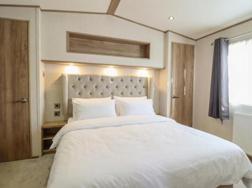 a bedroom with a large white bed with white pillows at 23 Gull Court in Porthmadog