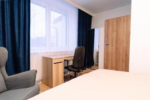 a bedroom with a bed and a desk and a chair at ApartHouse in Klimontów