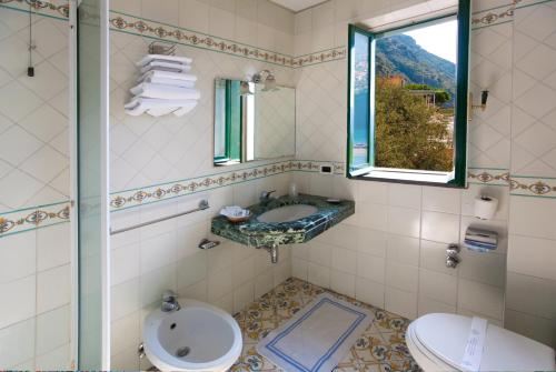 een badkamer met een wastafel, een toilet en een raam bij Hotel Mega Mare in Vico Equense