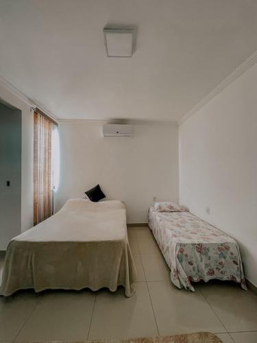a white room with two beds and a window at Suítes em casa ampla com área gourmet in Uberlândia