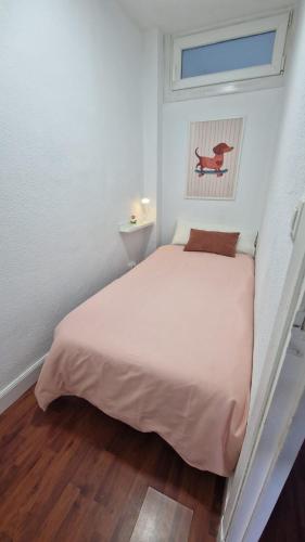 a small bedroom with a white bed and a window at Apartamento Gaztelugatxe in Bakio