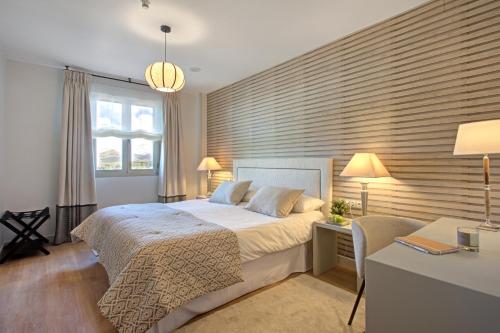 a bedroom with a large bed and a desk with a chair at Hotel Faisanera Golf in Palazuelos de Eresma