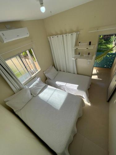 a small room with two beds and a window at Casa Aconchego do Mar in Japaratinga