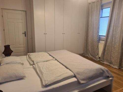 a bedroom with a bed with white sheets and a window at Oasis City Central in Tarnowskie Góry