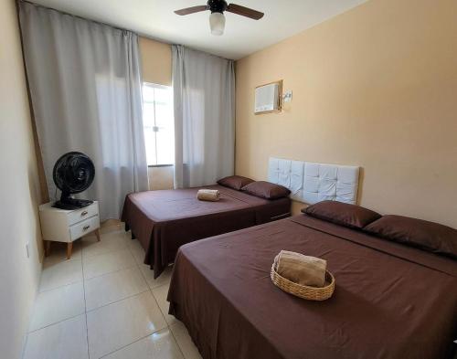 two beds in a hotel room with a fan at Casa Marinho - Pé na praia in Saquarema