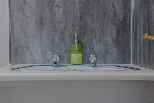 a bathroom sink with a bottle of green liquid at Castle Inn in Newtownstewart