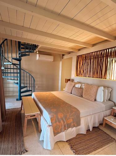 a bedroom with a large bed and a staircase at Estalagem Caiuia in Japaratinga
