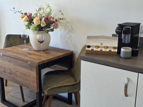 a table with a vase of flowers and wine glasses at Littlestone Seaside Retreat in Littlestone-on-Sea