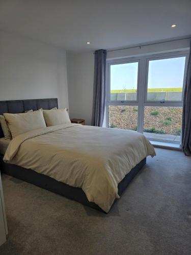 a bedroom with a large bed with a large window at Littlestone Seaside Retreat in Littlestone-on-Sea