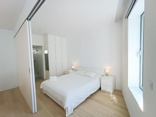 a white bedroom with a white bed and a mirror at Ria & Mar Collection I in Aveiro