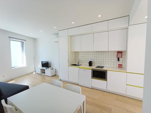 a kitchen with white cabinets and a table at Ria & Mar Collection I in Aveiro