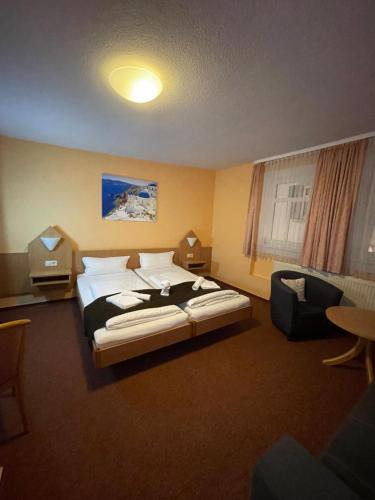 a hotel room with a large bed and a chair at Poseidon Hotel in Hirschhorn