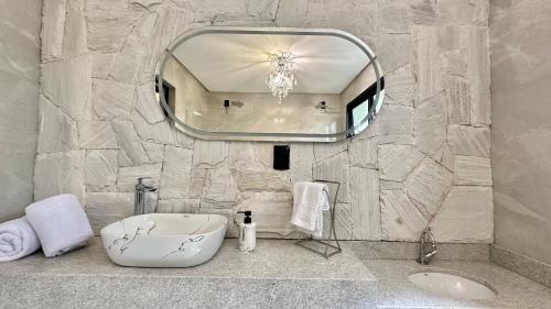 a bathroom with a large mirror and a sink at Chalé Rio das Pedras - Chalé 03 in Chapecó