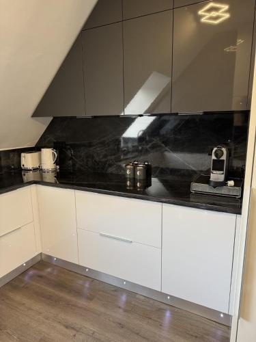 a kitchen with white cabinets and black counter tops at Central Vibe Apartman in Kecskemét