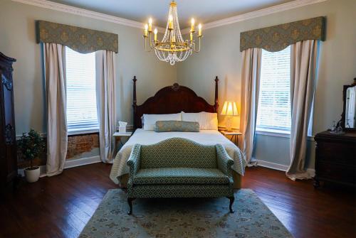 a bedroom with a bed and a chair and a chandelier at Ormond Manor in Destrehan