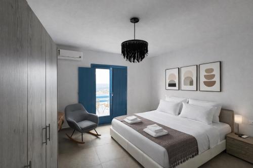 a bedroom with a bed and a chair and a window at Amuse Mykonos Apartments By Vilanel Group in Mikonos