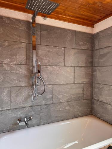 a bath tub in a bathroom with a stone wall at La Rose d Eva in Saint-Martin