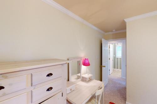 a bedroom with a dresser and a table with a lamp at Seaside Sea Esta in Corolla