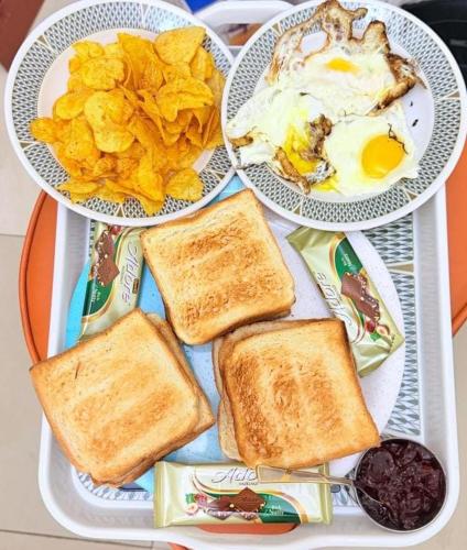 two plates of food with toast and eggs and chips at Cozy 1 Bedroom Hall in Khor Fakkan