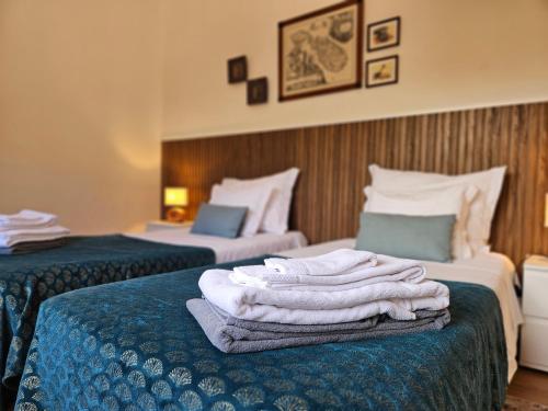 a hotel room with two beds with towels on them at A Casa do Comandante - Piscina e Jardim in Lagoa