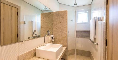 a bathroom with a sink and a mirror and a shower at Tauá Hotel & Convention Caeté in Roças Novas