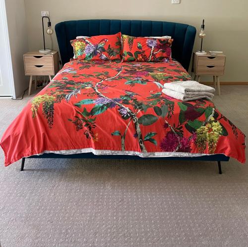 a bed with a red comforter and pillows at Birdsong Gardens in Quorn