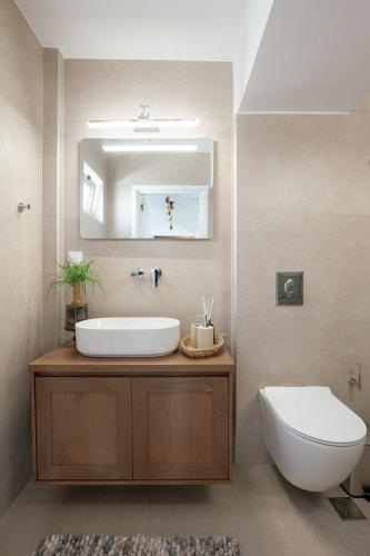 a bathroom with a sink and a toilet and a mirror at Skyloft - Rooftop Jacuzzi & Sea View - Central Kos in Kos