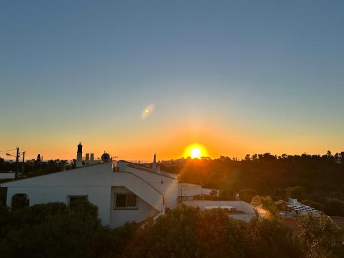 a sunset over a white building with the sun in the background at Villa Tara Christina in Carvoeiro