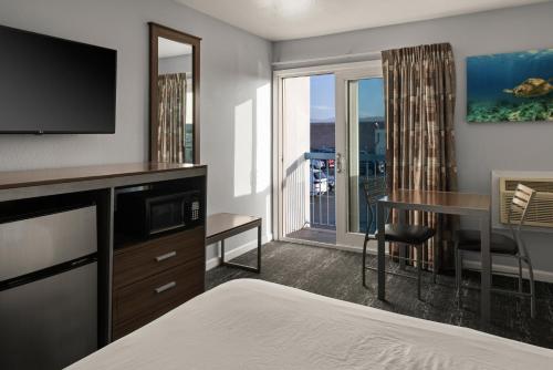 a hotel room with a bed and a desk with a television at Sand Dollar Inn in Seaside