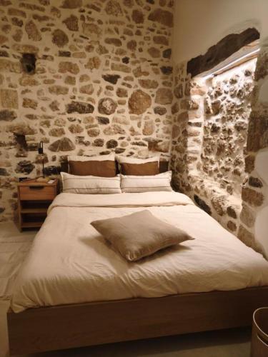 a bedroom with a large bed with a stone wall at ARETOUSA Private Village Suite in Sitia