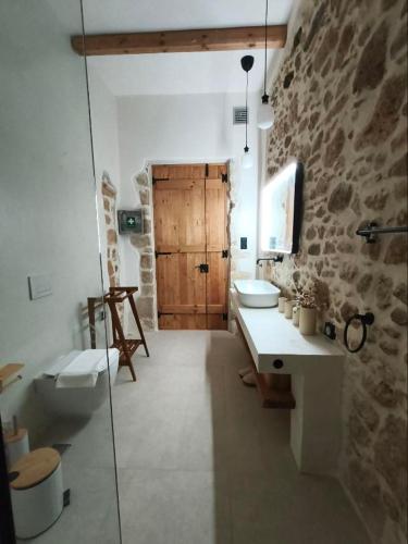 a bathroom with two sinks and a stone wall at ARETOUSA Private Village Suite in Sitia