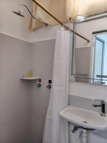 a white bathroom with a sink and a mirror at Galápagos Finch Apartment in Puerto Ayora