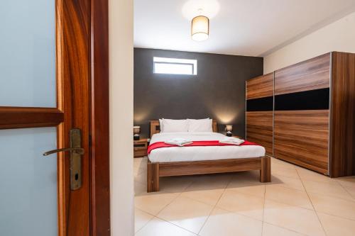 a bedroom with a bed with a wooden headboard at Mandalay Cozy & Affordable Apartment with Patio in Mellieħa