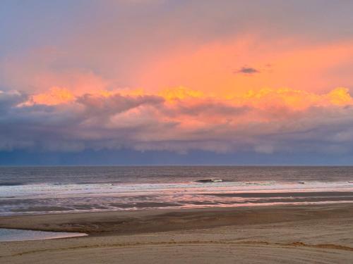 a beach with a cloudy sky and the ocean at 54 George Street in Mablethorpe