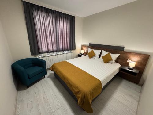 a hotel room with a bed and a blue chair at Guest houses Forte in Tsigov Chark