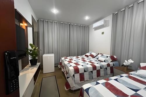 a hotel room with two beds and a television at Studio Sol in Mossoró