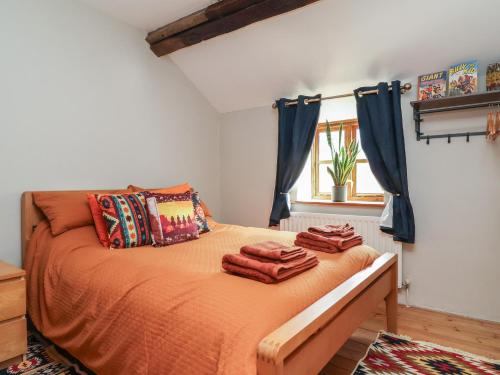 a bedroom with a bed with orange sheets and blue curtains at The Ranch in Prestatyn