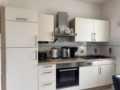 a white kitchen with white cabinets and appliances at Ferienwohnung in Ballenstedt in Ballenstedt