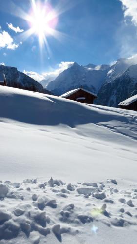 a snow covered slope with the sun in the sky at Chalet Safran in Grächen