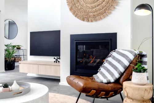 a living room with a leather chair and a fireplace at Super-Styled Light-Filled Eco Home in Torquay
